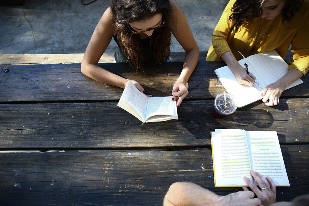 Three students reading at a picnic table